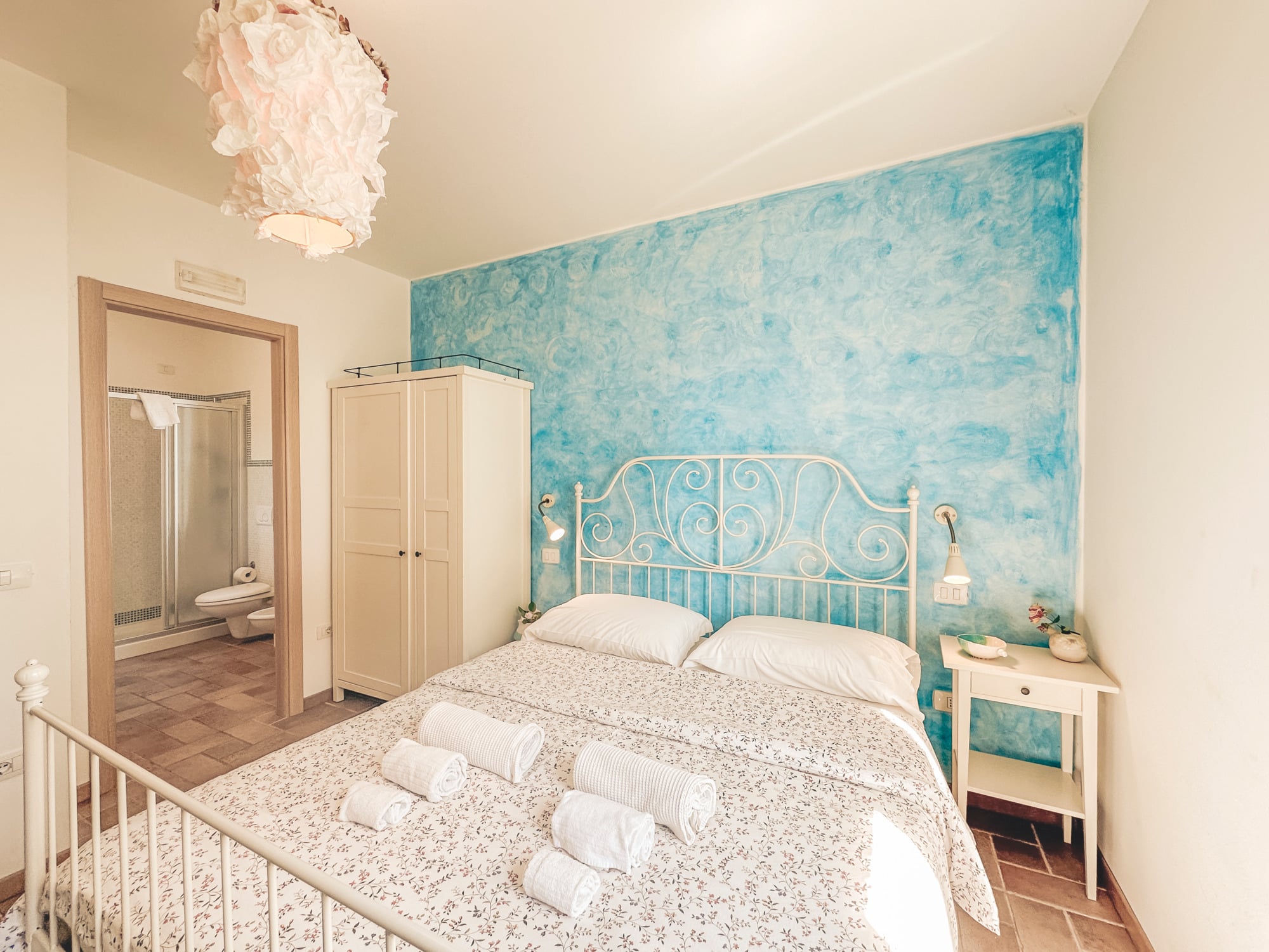 Camera con parete azzurra e letto in ferro battuto bianco