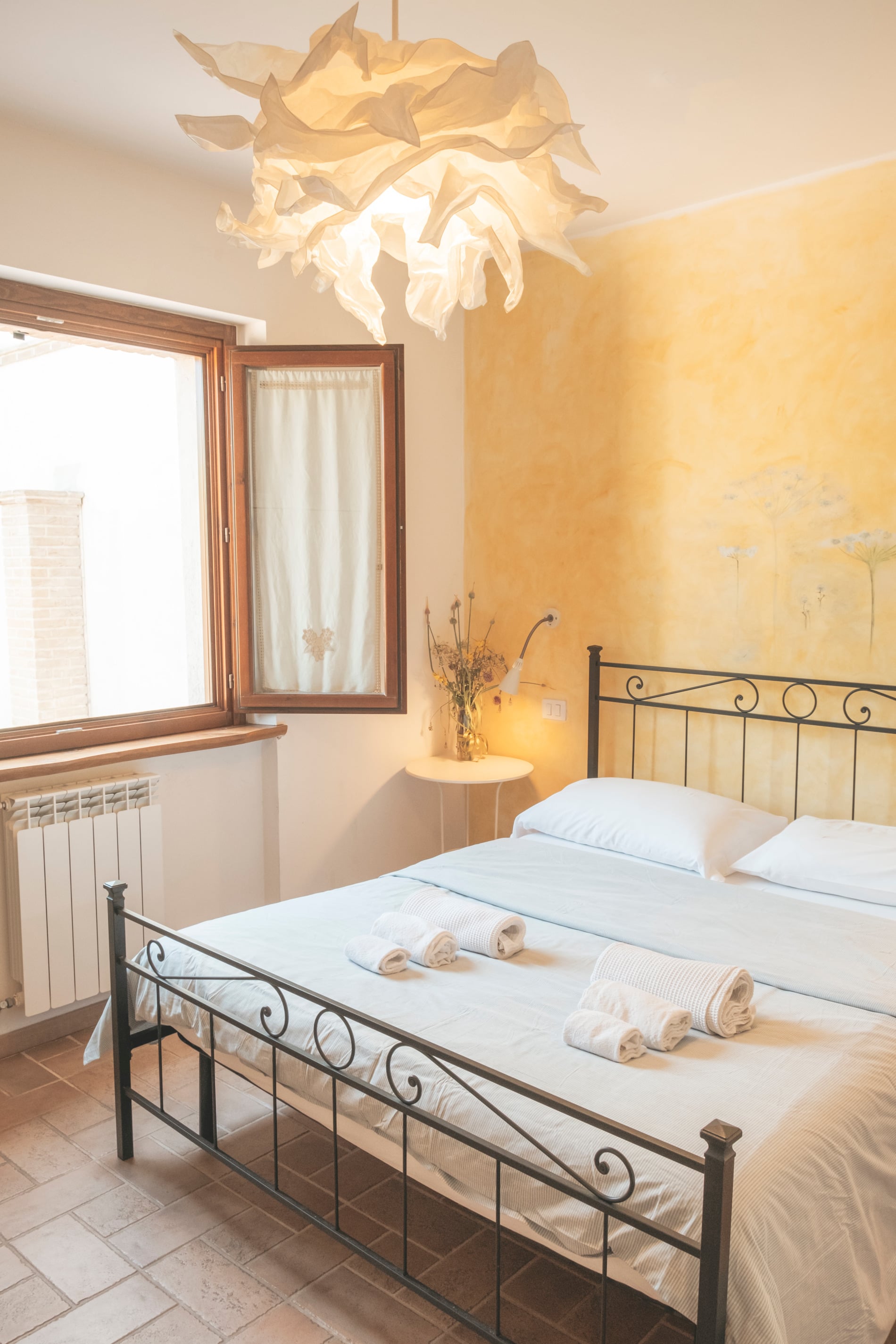 Camera con pareti color miele e letto in ferro
