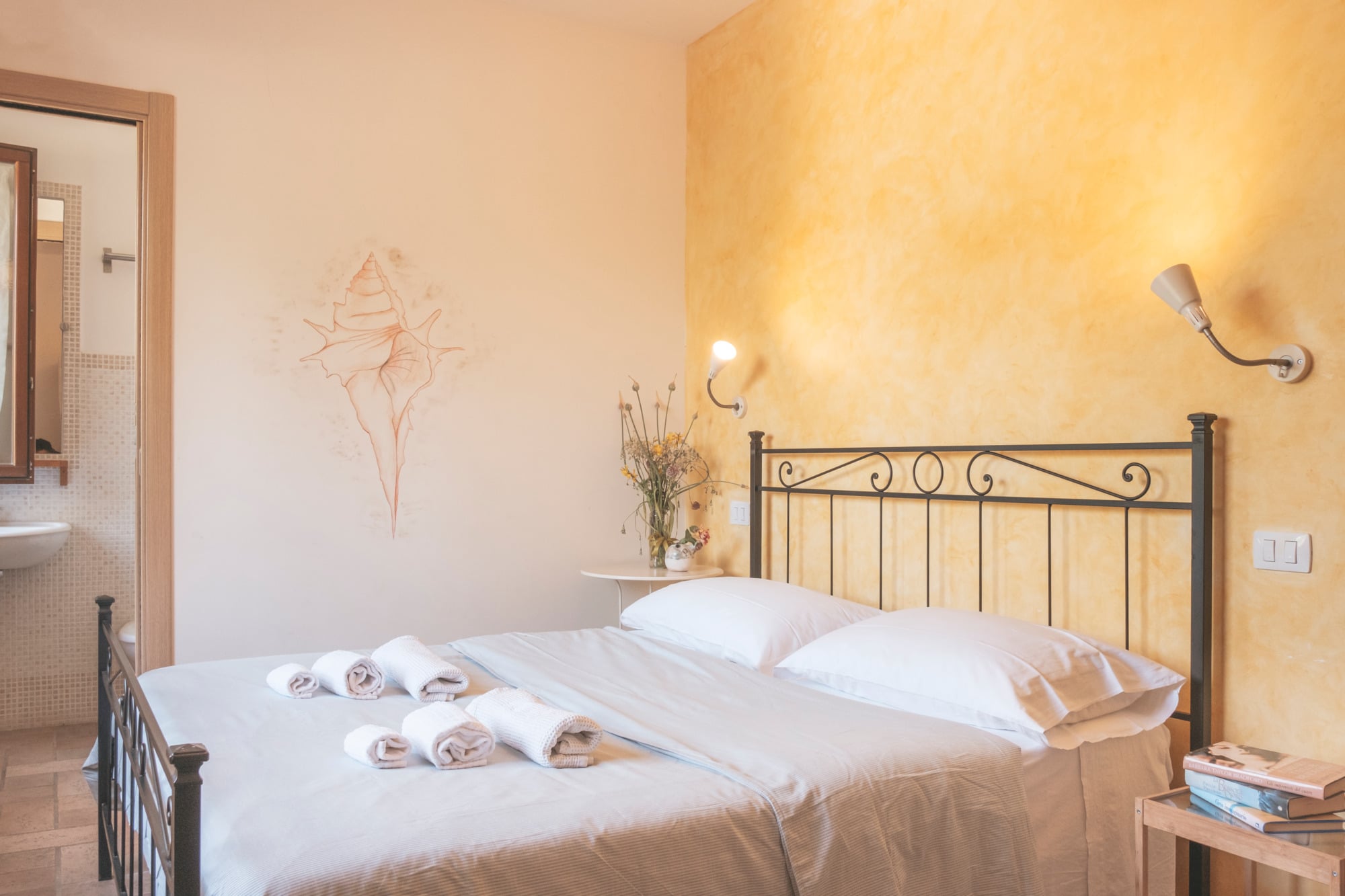 Camera gialla con comodini e asciugamani sul letto