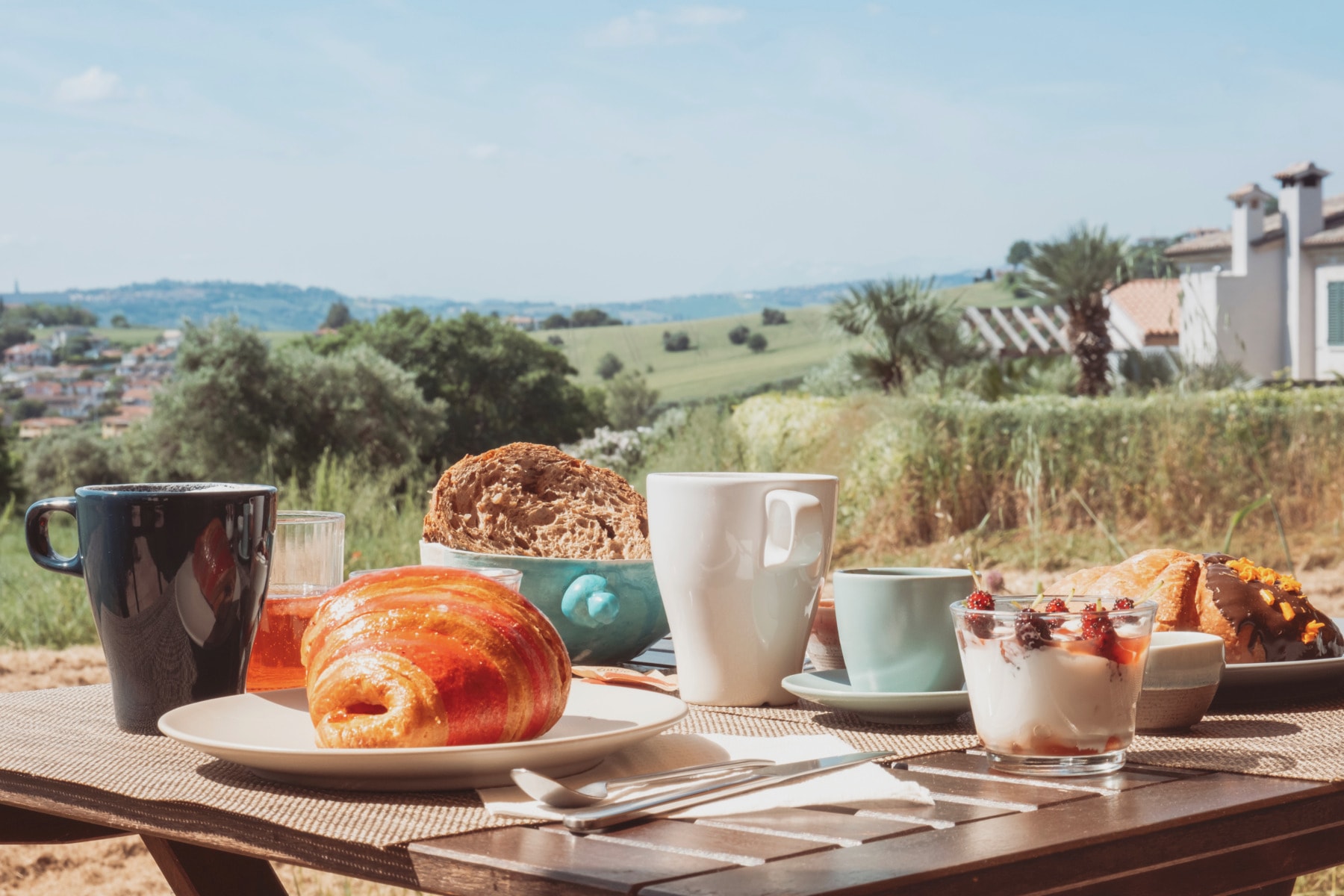 Colazione sul tavolo all'aperto: cornetto, yogurt e caffè